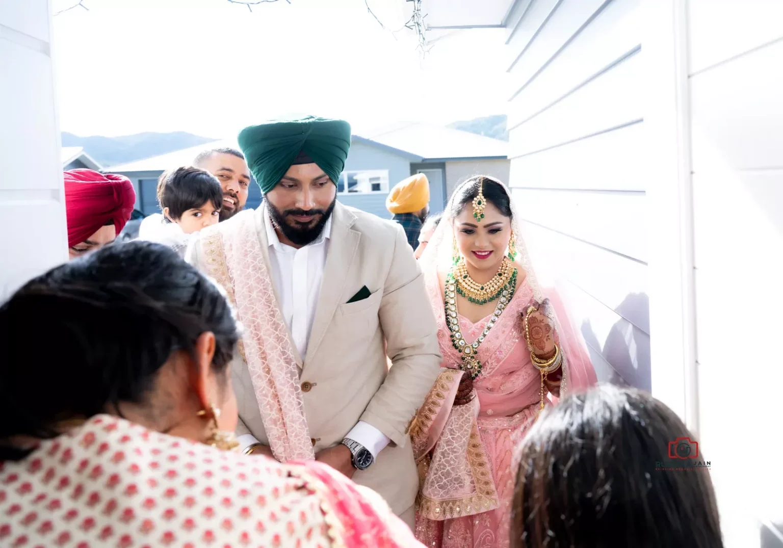 Bride and groom entering a house during a traditional ceremony, with family members gathered around them