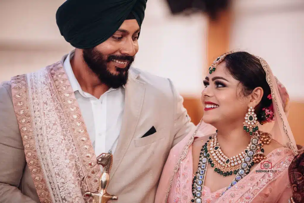 Bride and groom in traditional attire smiling at each other during their wedding ceremony