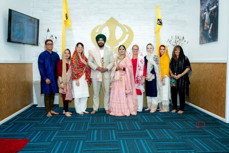 Bride and groom posing with guests in traditional attire at a Sikh wedding