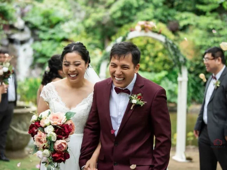 Bride and groom smiling and walking together in a garden after their wedding ceremony