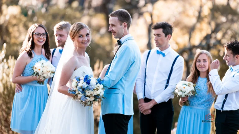 Bride and groom smiling with bridal party dressed in blue and white