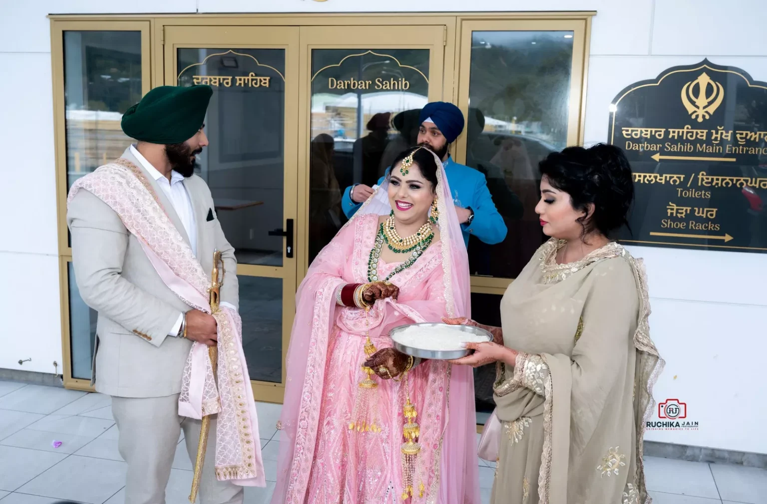 Bride and groom smiling with friends outside Darbar Sahib at a Sikh wedding