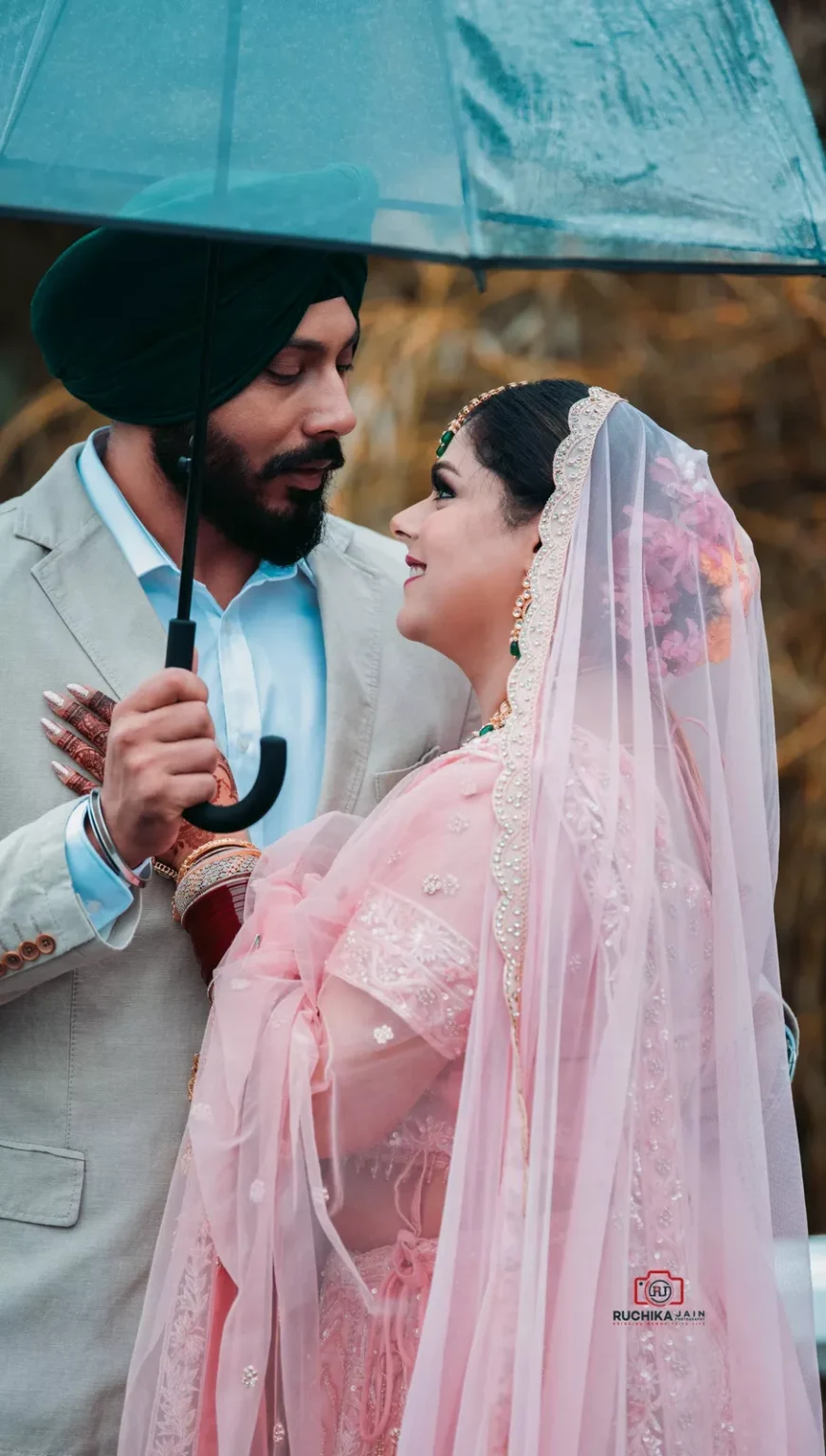 Bride and groom standing under an umbrella, gazing at each other, during an outdoor photoshoot