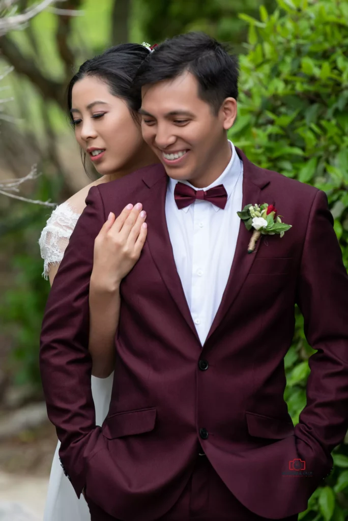 Bride embracing groom from behind in a Wellington garden setting