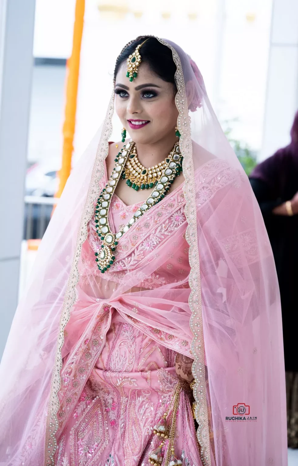 Bride in a pink embroidered lehenga smiling during a Sikh wedding ceremony