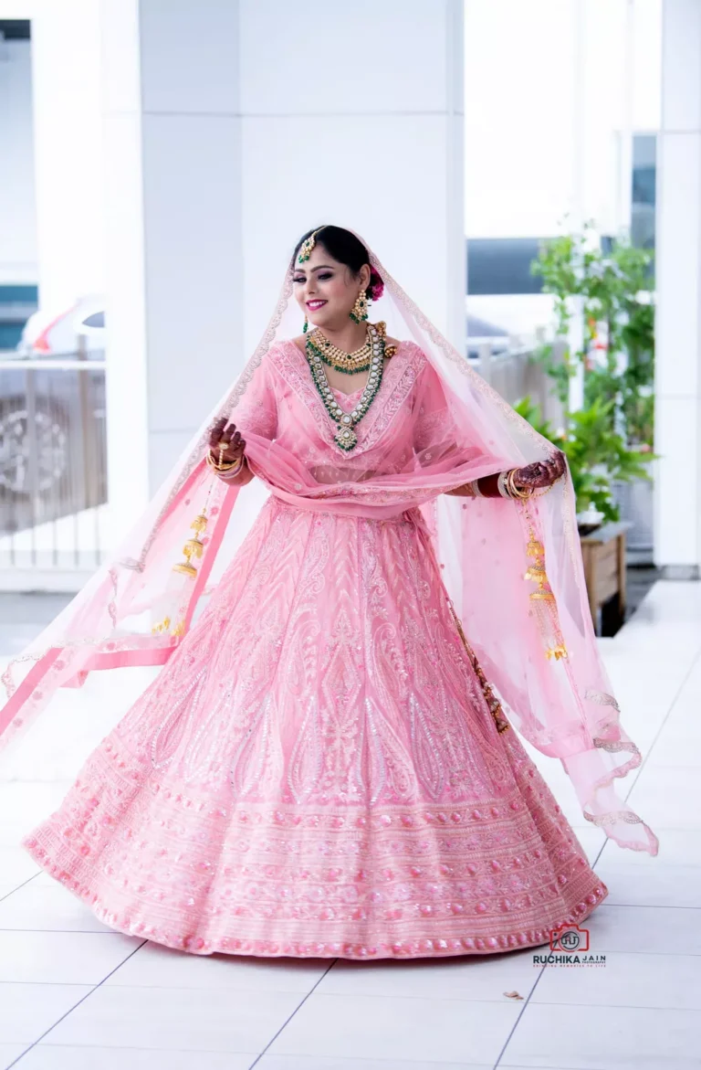 Bride in a pink traditional wedding outfit twirling during a Sikh wedding