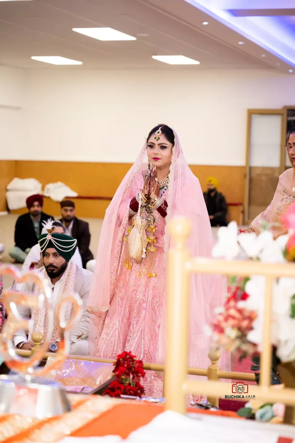 Bride in pink lehenga walking around the altar during a Sikh wedding ceremony