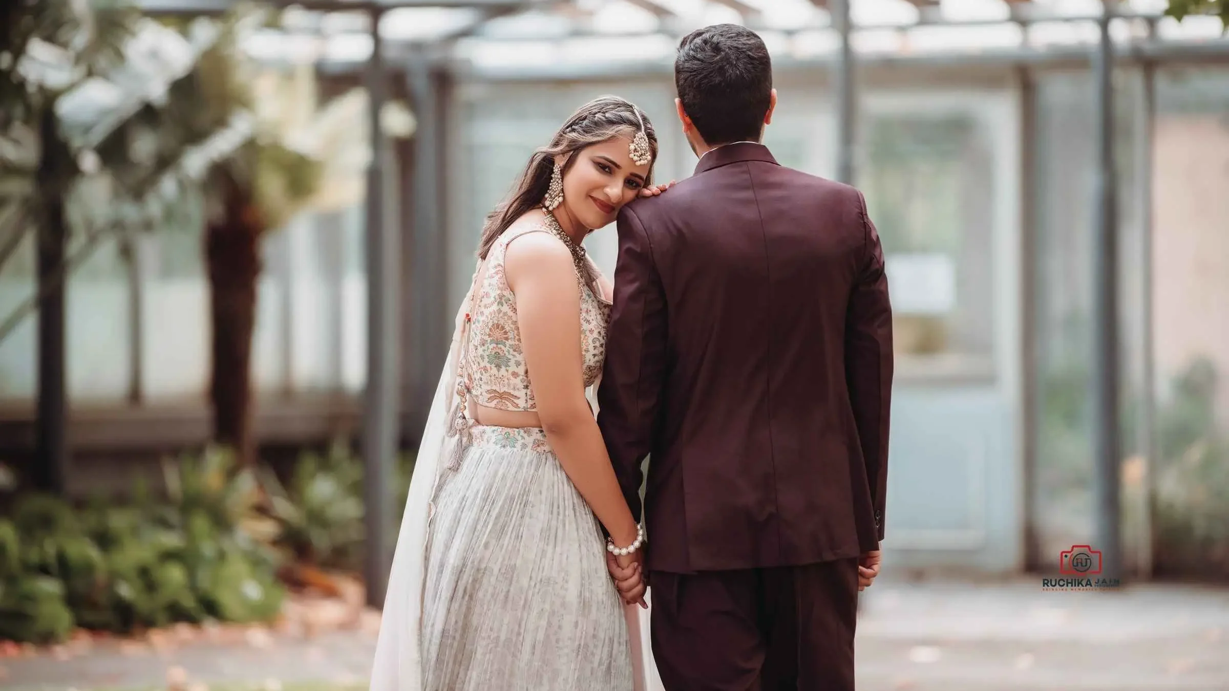 Bride leaning on groom's shoulder with a soft smile, holding hands, standing outdoors