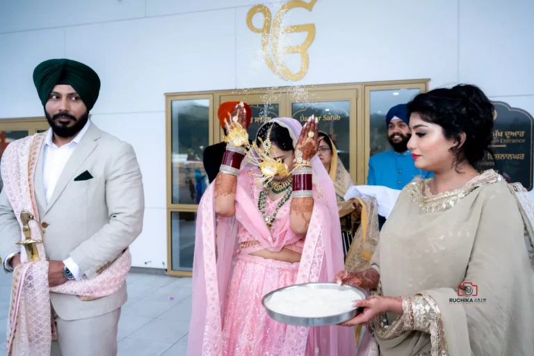 Bride performs traditional rice throwing ritual while groom and guests stand outside Darbar Sahib at a Sikh wedding