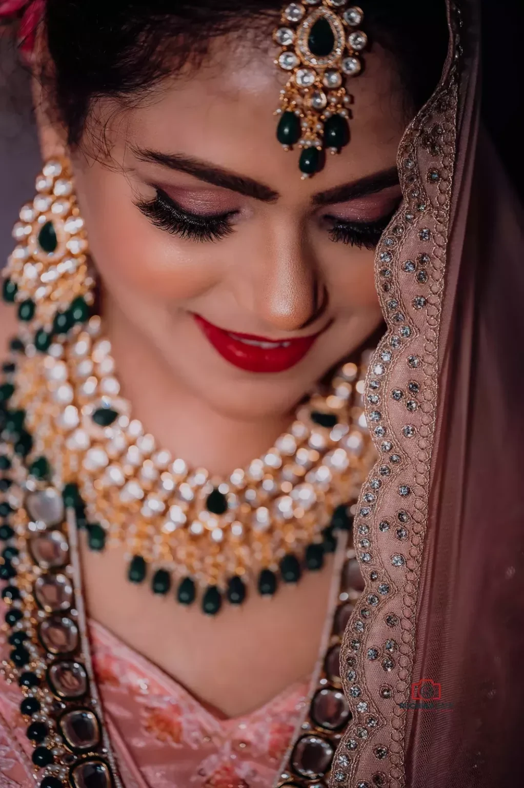 Bride wearing intricate jewelry and a jeweled veil, smiling softly