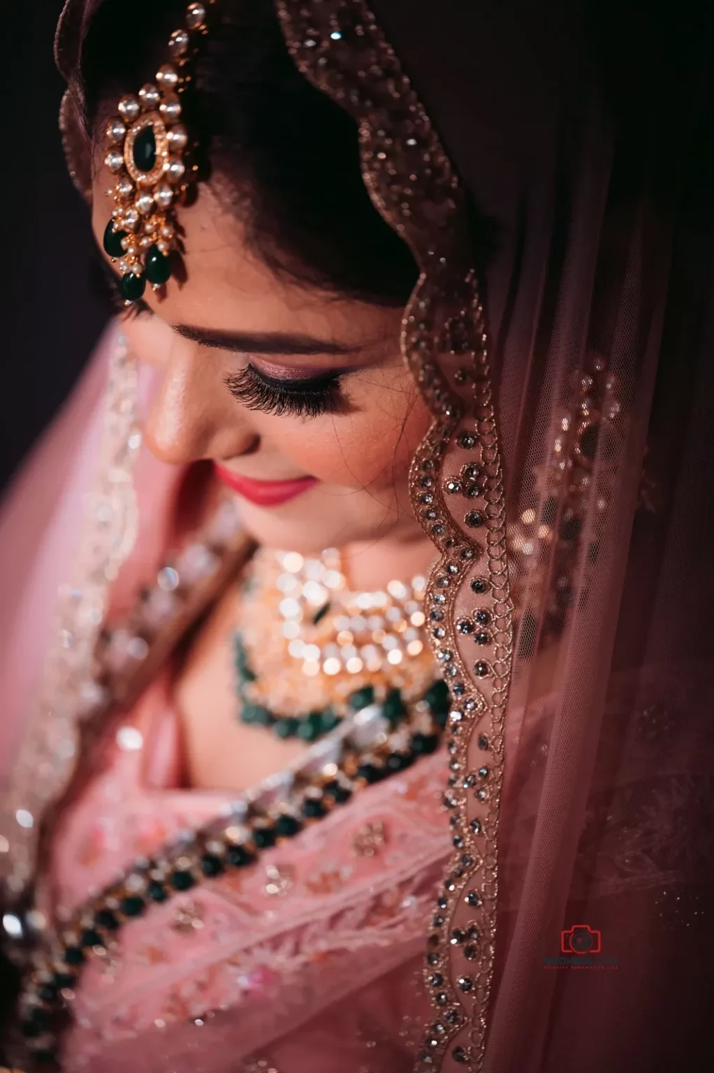 Close-up of a bride in traditional attire with jeweled veil, showing detailed makeup, jewelry, and intricate embroidery