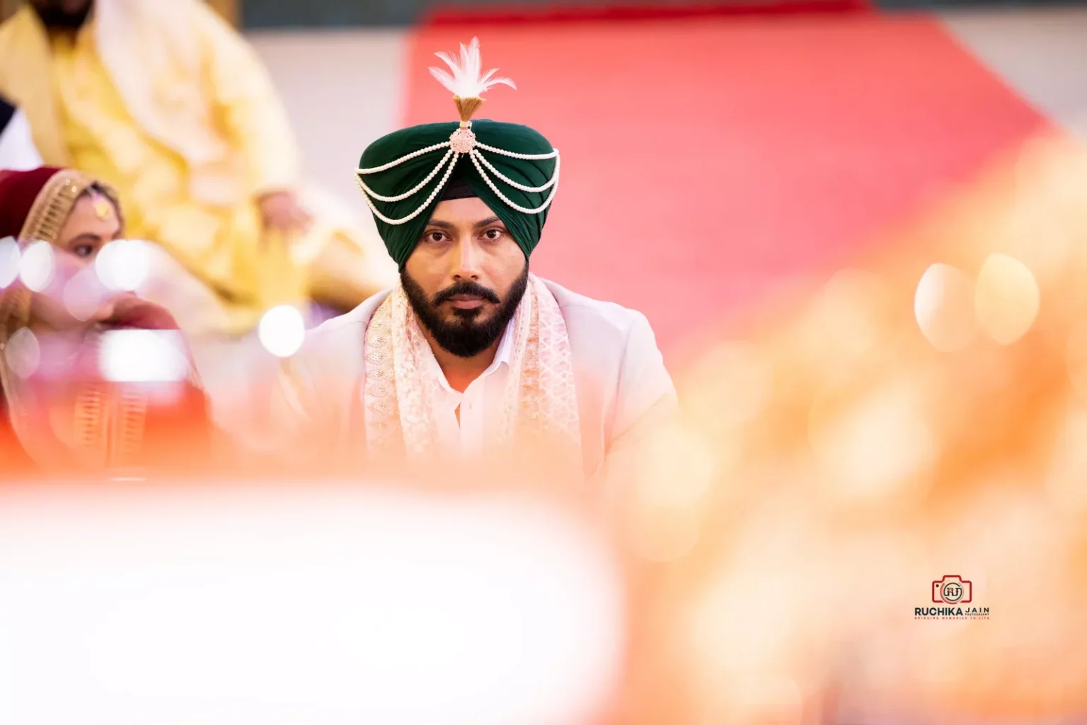 Groom in green turban seated solemnly during a Sikh wedding ceremony