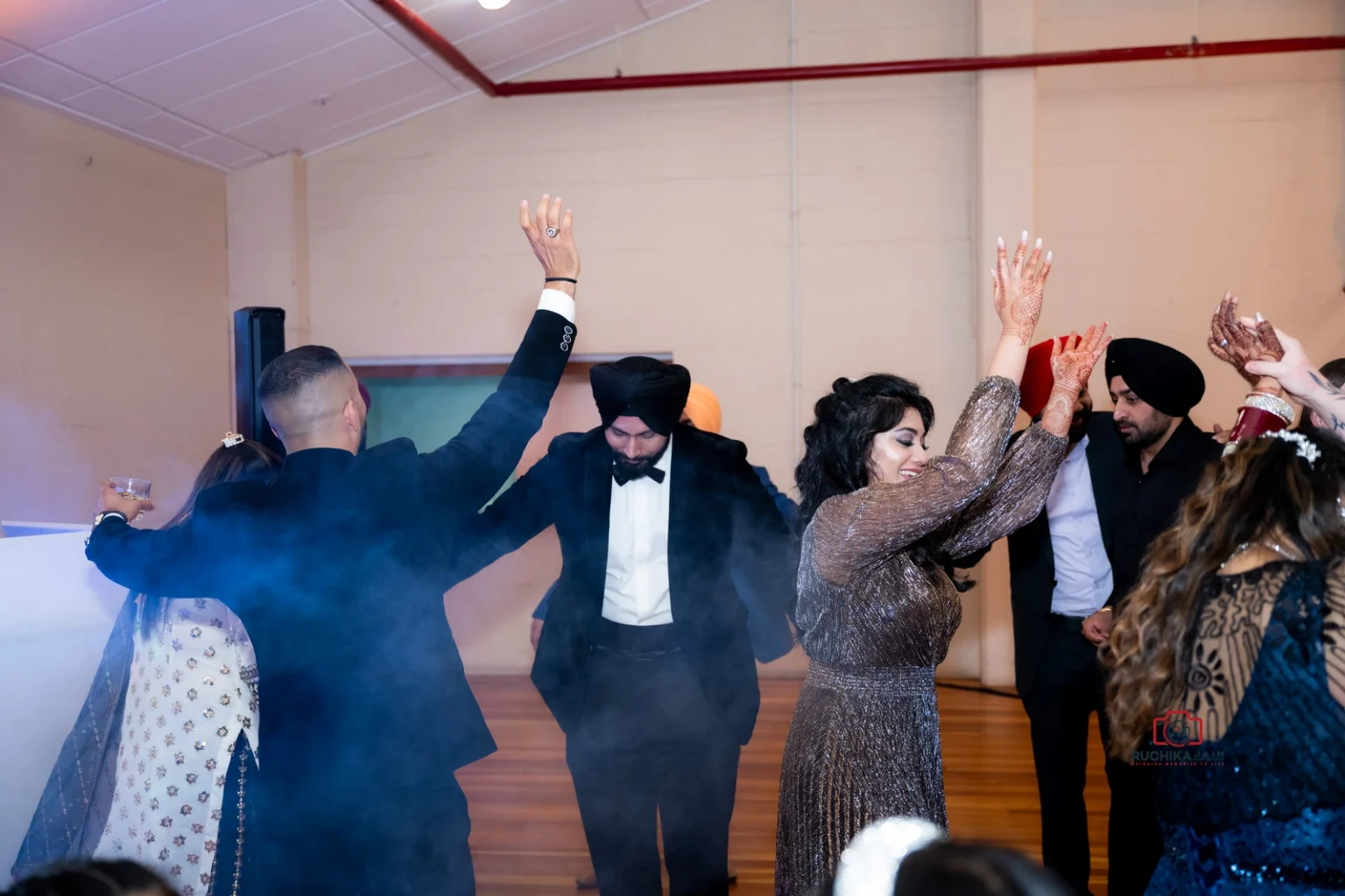 Group of people dancing at a celebration with raised arms and smiling faces