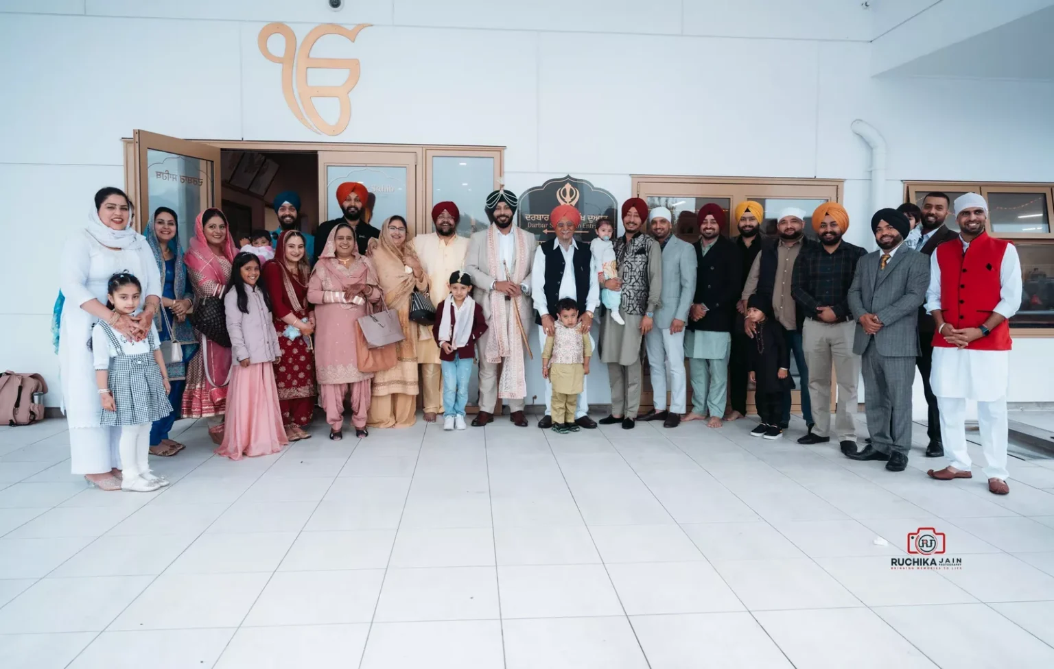 Large family group posing together outside a Gurdwara after a wedding ceremony