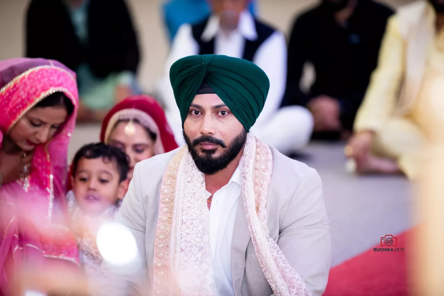 Sikh groom wearing a green turban sitting during wedding ceremony