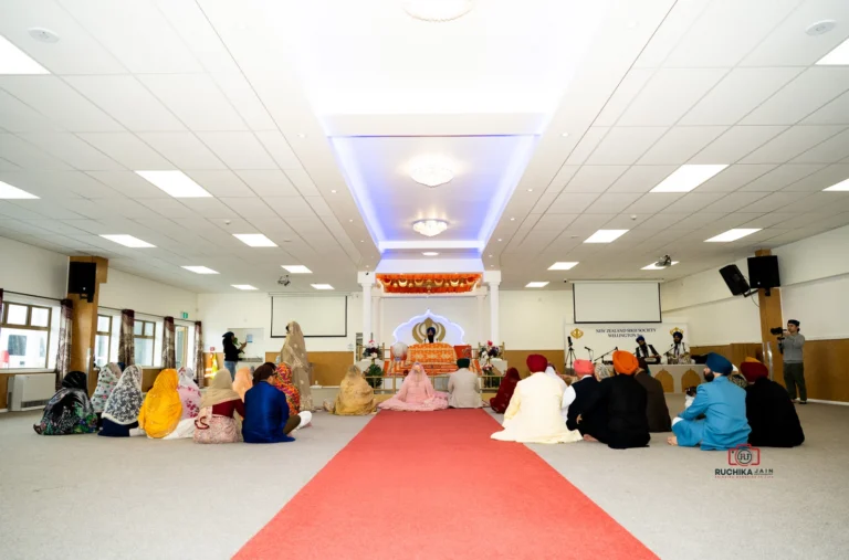 Sikh wedding ceremony at New Zealand Sikh Society Wellington with bride, groom, and guests seated facing the Guru Granth Sahib