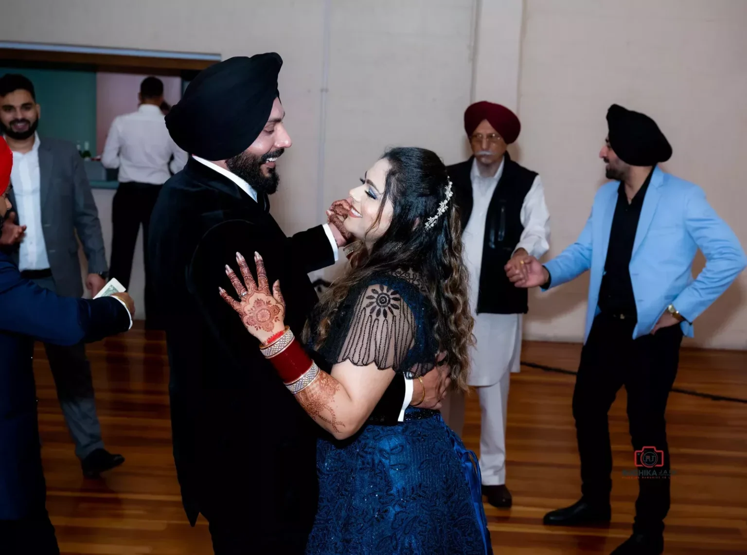 Smiling couple dancing together at an indoor event with other guests in the background