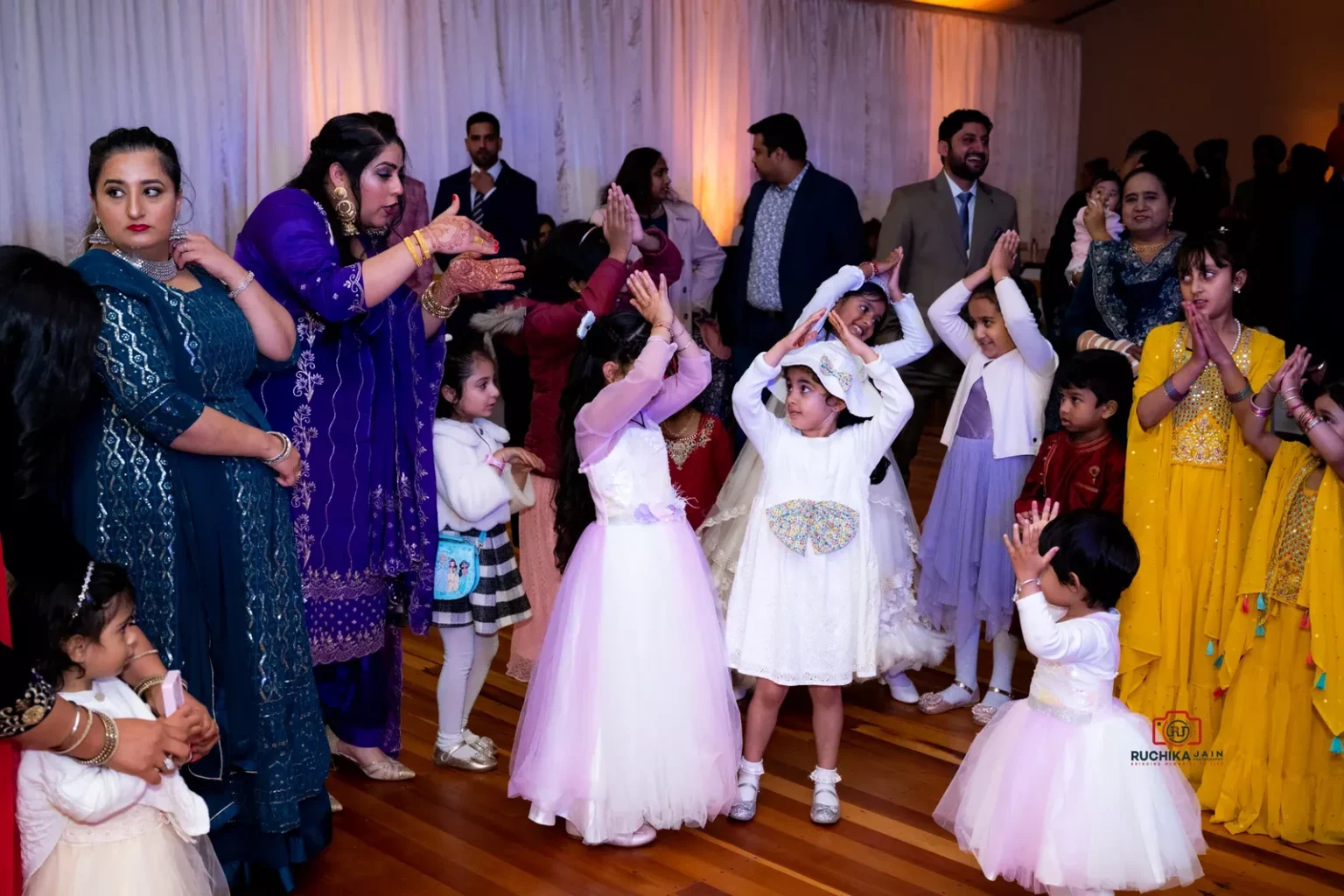 Group of children in vibrant outfits dancing and enjoying a lively wedding celebration in Wellington.