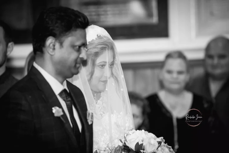 Bride in veil holding bouquet, walking down the aisle with her father during wedding ceremony