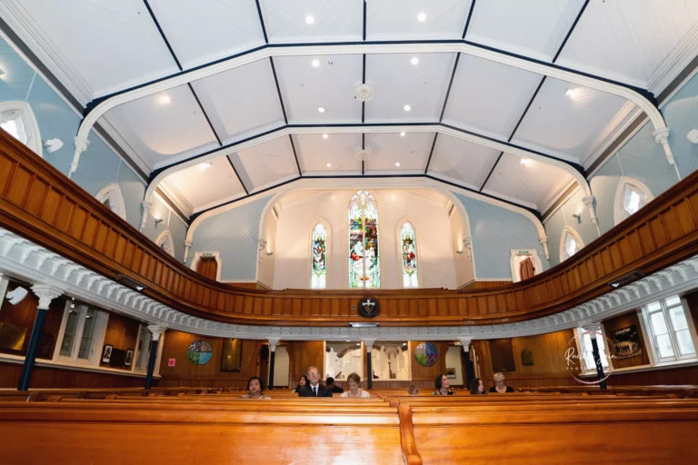 Interior of a traditional church with wooden pews and ornate stained glass windows, showcasing a spacious and serene atmosphere