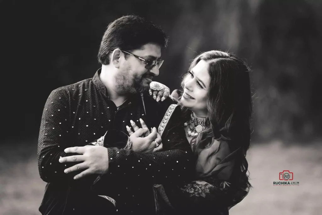 A black and white photograph of a couple smiling warmly at each other, captured in an affectionate embrace, showcasing their love and connection.