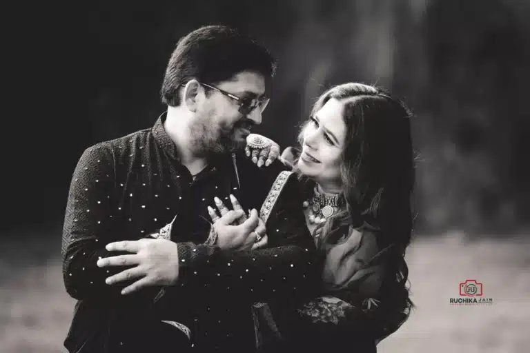 A black and white photograph of a couple smiling warmly at each other, captured in an affectionate embrace, showcasing their love and connection at The Lodge Pāuatahanui Wellington.