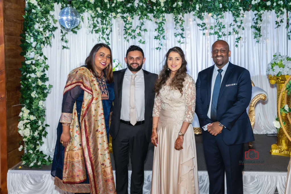 Bride, groom, and two guests posing at a wedding reception with a floral and greenery backdrop in Wellington, New Zealand