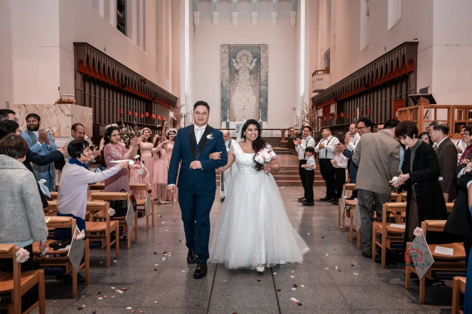 Bride and groom walking arm in arm down the aisle with smiling guests on either side