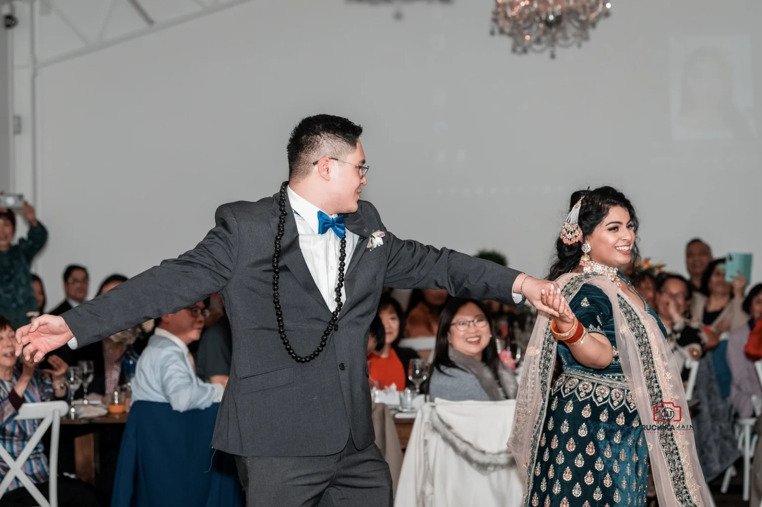 Bride and groom smiling and holding hands during their first dance at the wedding reception.