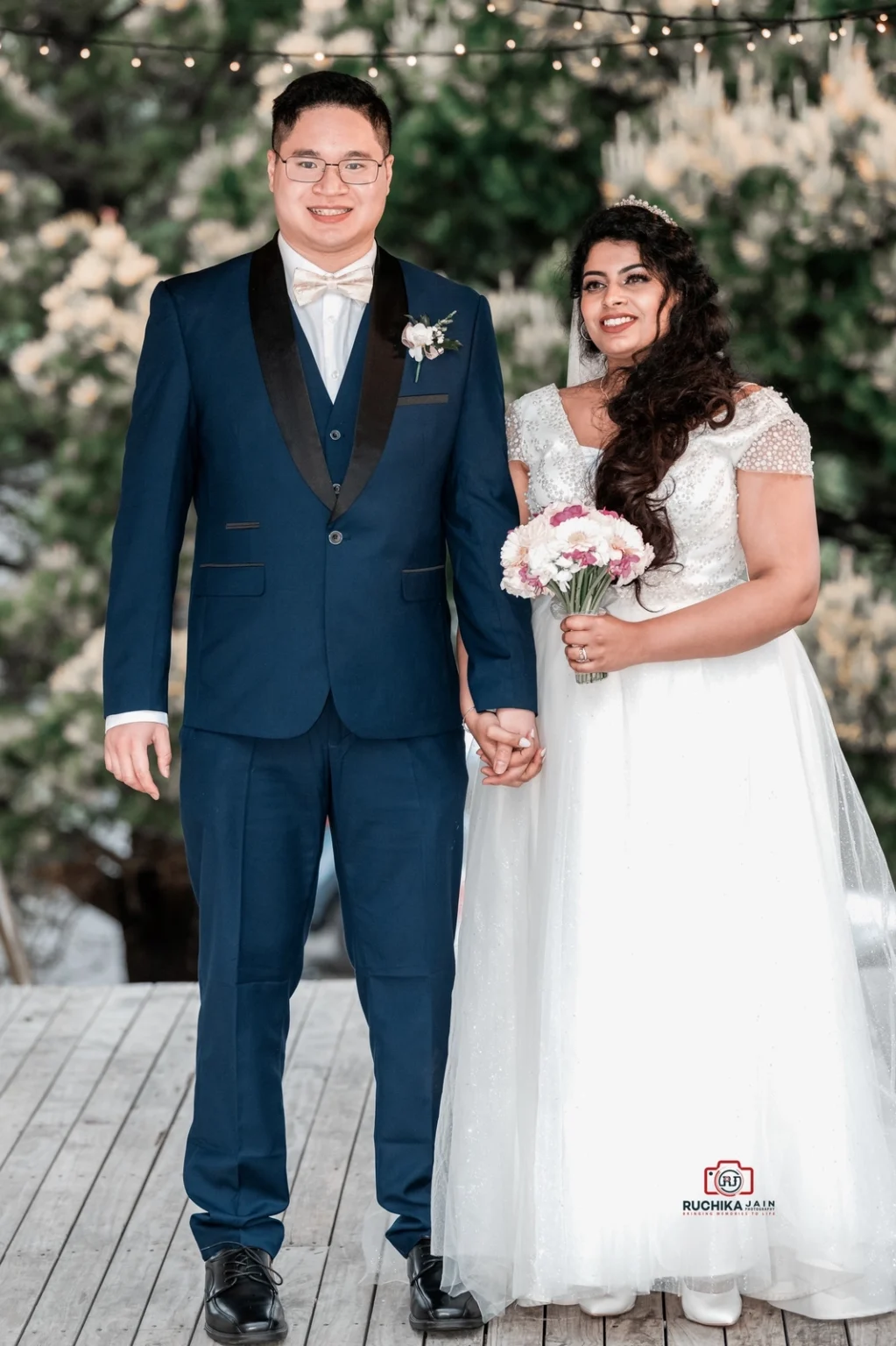 Bride and groom holding hands outdoors, both smiling and dressed in wedding attire