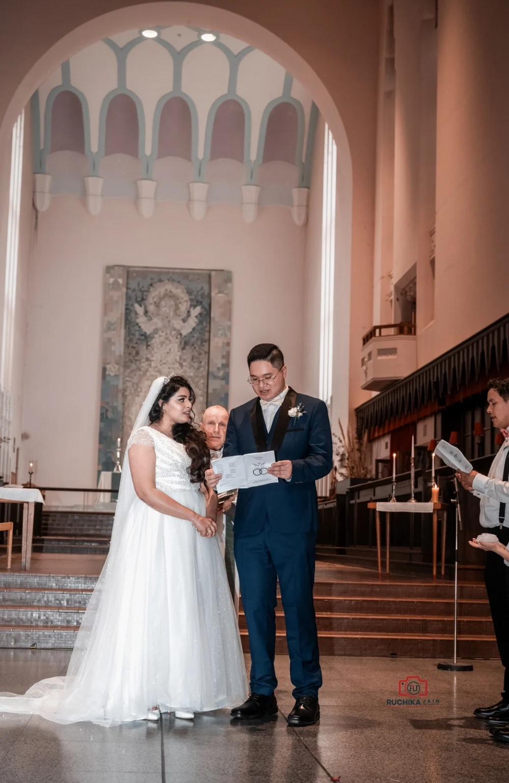 Bride and groom exchange vows during a wedding ceremony in a large church with high arched ceilings