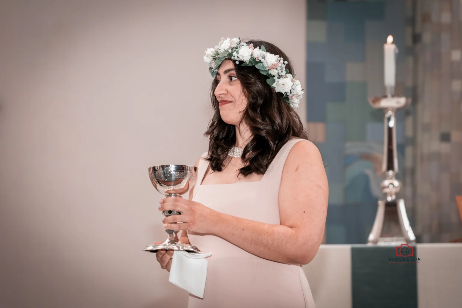 Bridesmaid with floral crown holding a communion chalice at a wedding ceremony