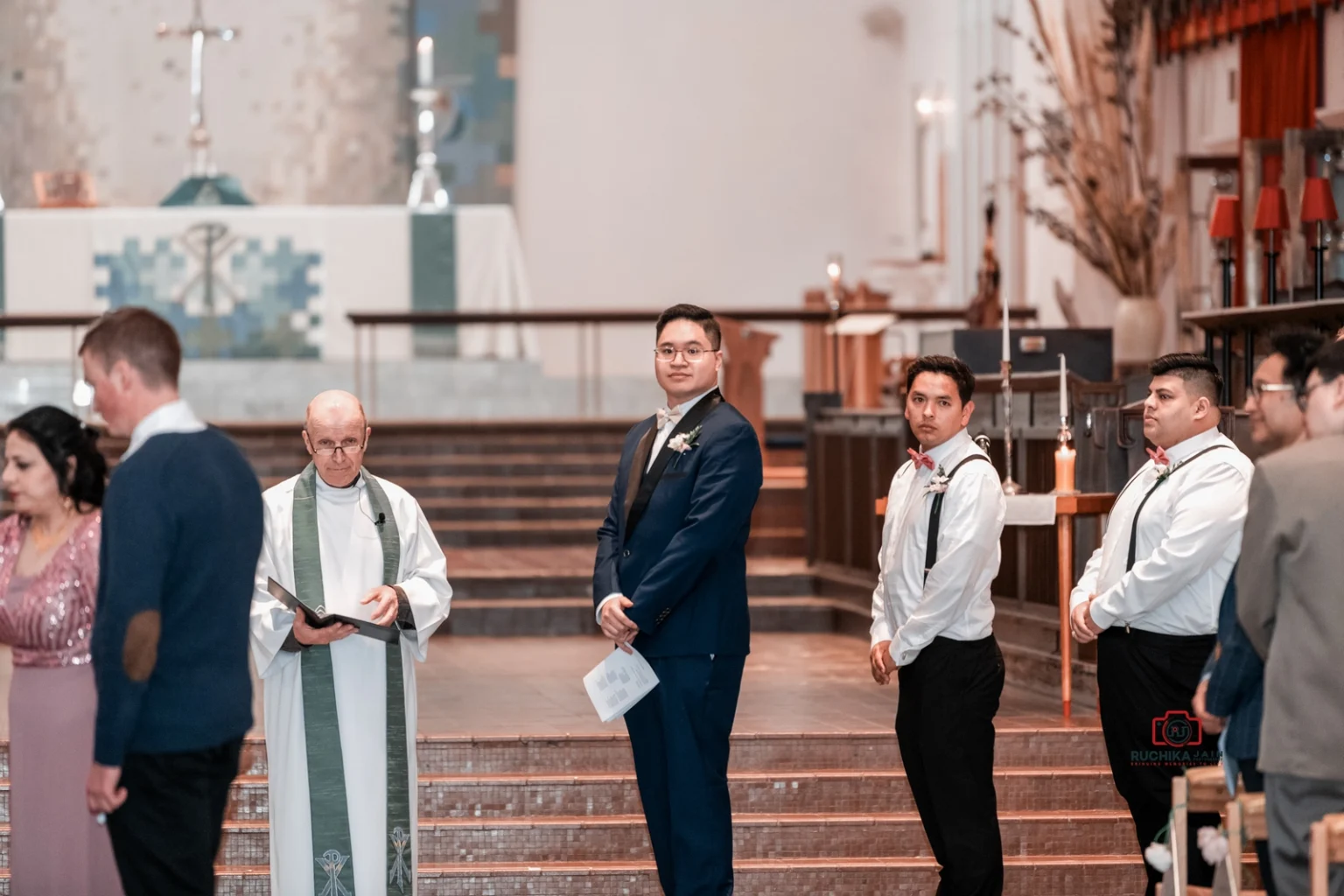 Groom standing at the altar with groomsmen and priest, awaiting the bride's entrance.