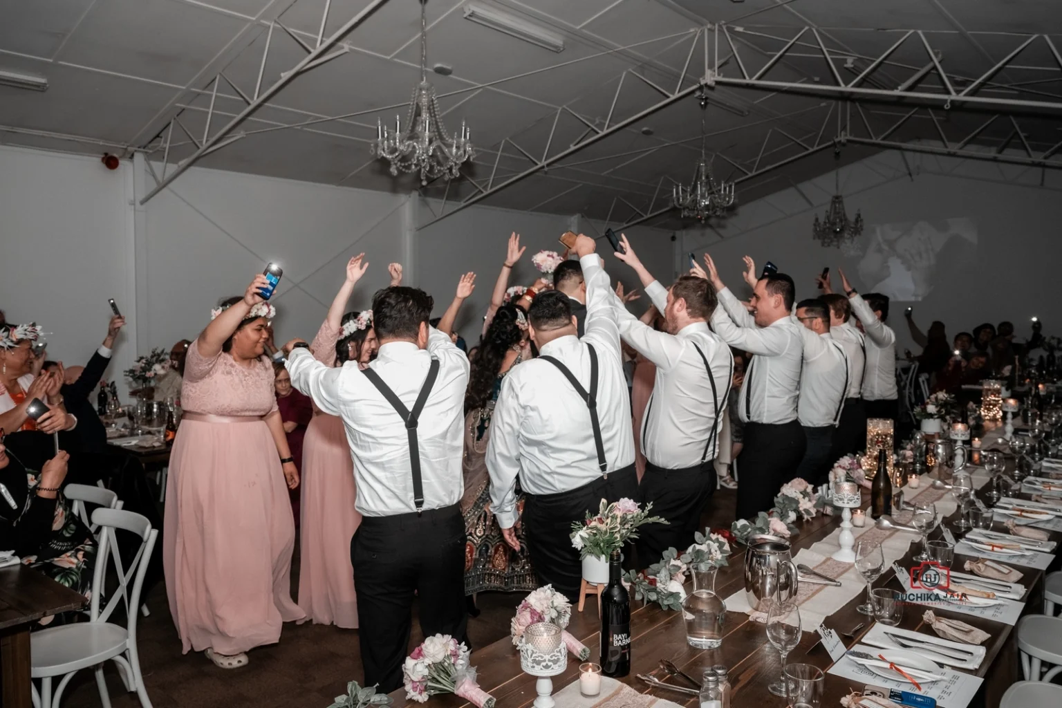 Wedding guests surrounding the bride and groom on the dance floor, cheering with raised arms