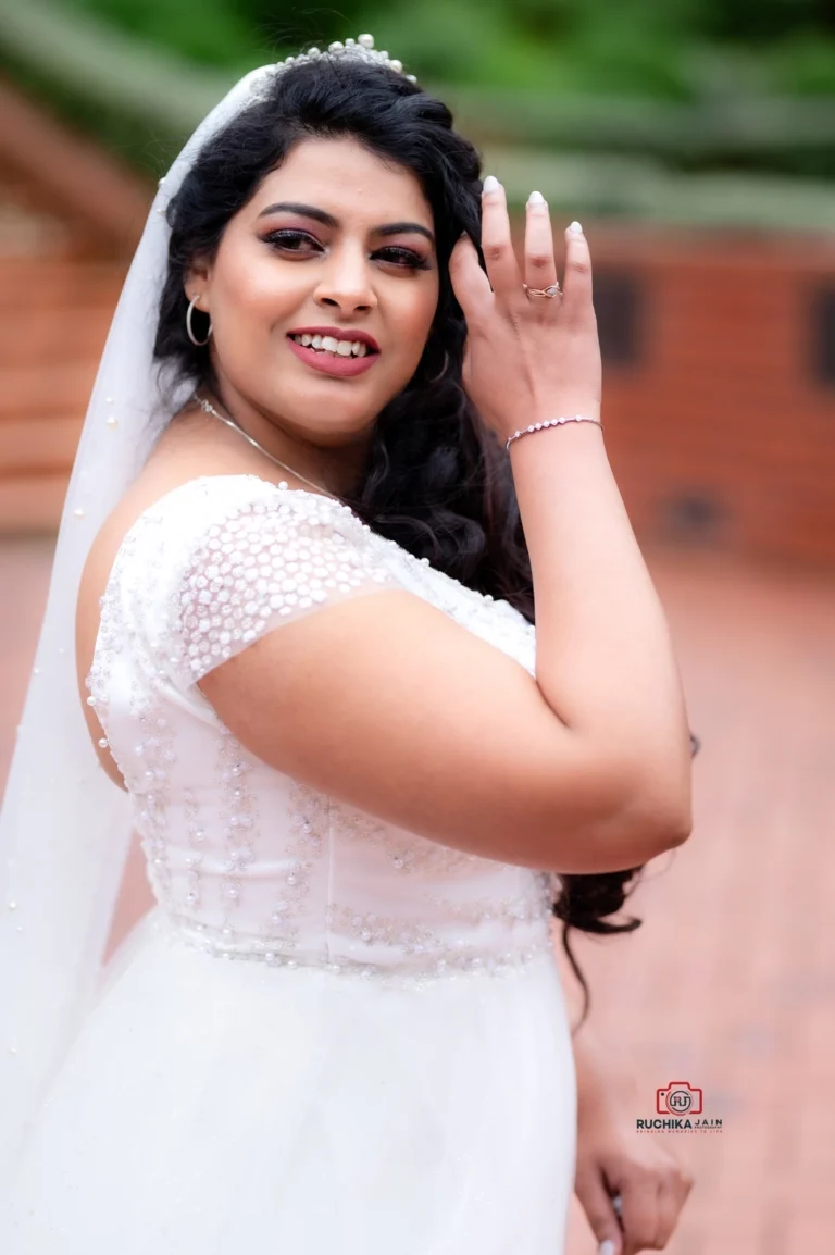 Bride in a beaded white dress smiling and adjusting her hair