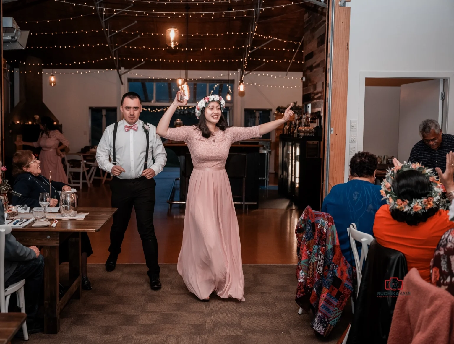 Wedding guests celebrate with dancing and laughter in a warmly lit reception hall