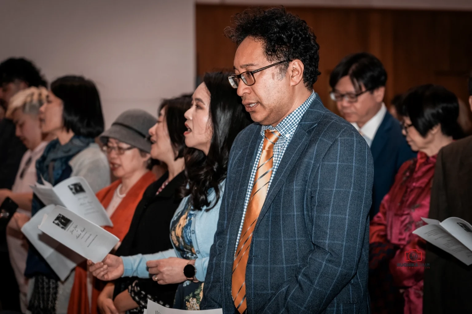 Guests holding booklets and singing during a wedding ceremony