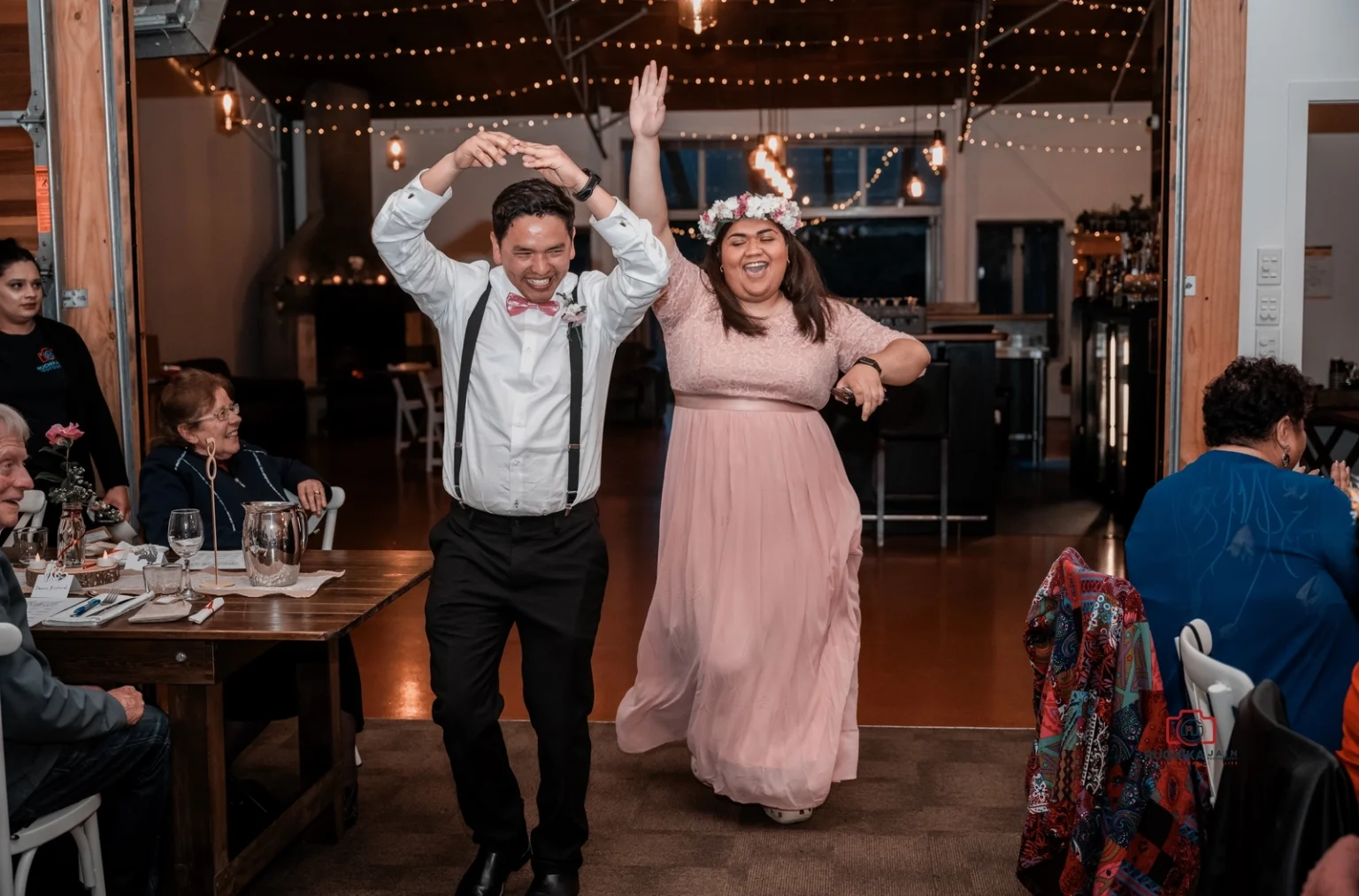 Wedding guests dancing joyfully at a reception, with the man spinning his partner