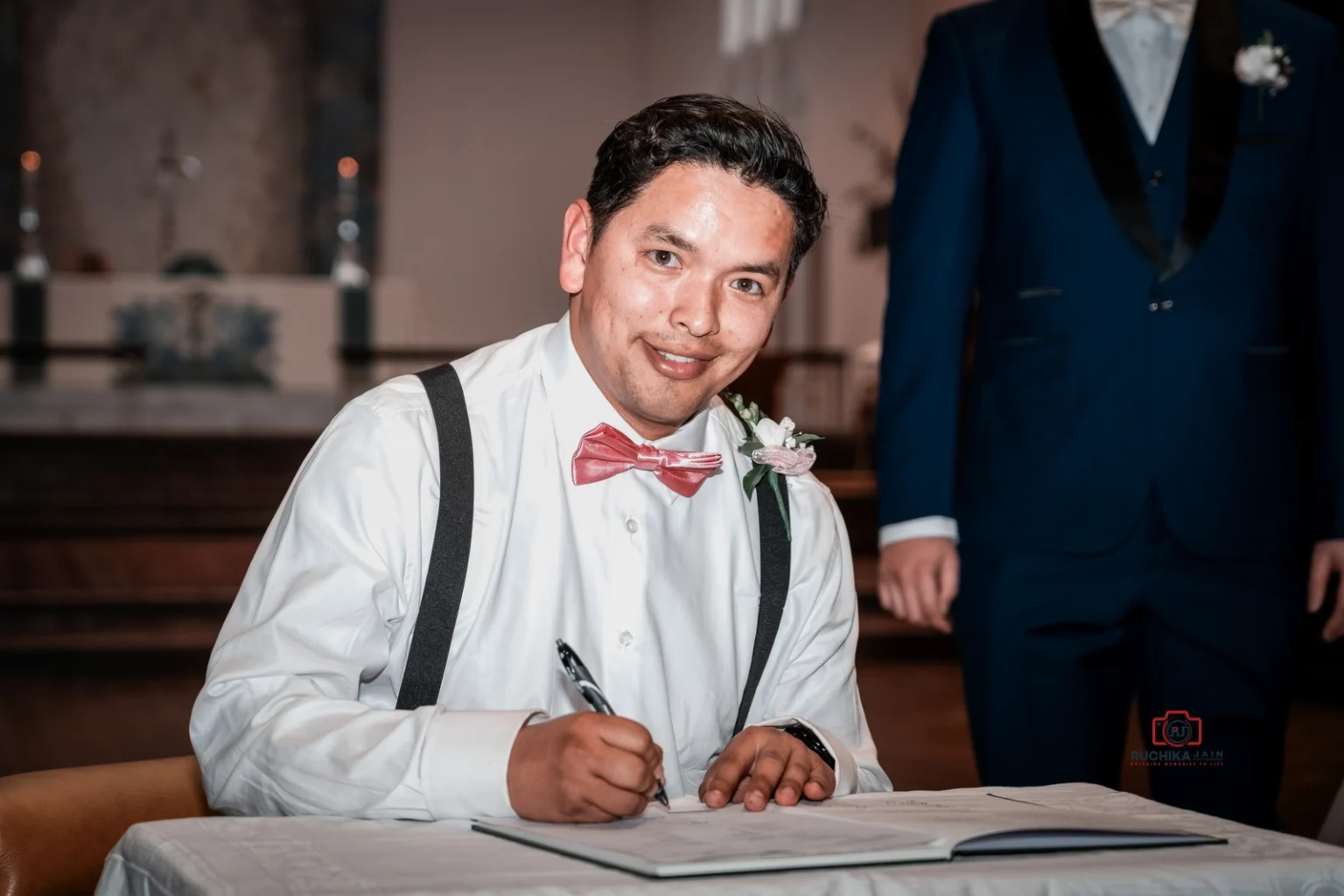 Wedding witness in pink bow tie signing marriage certificate