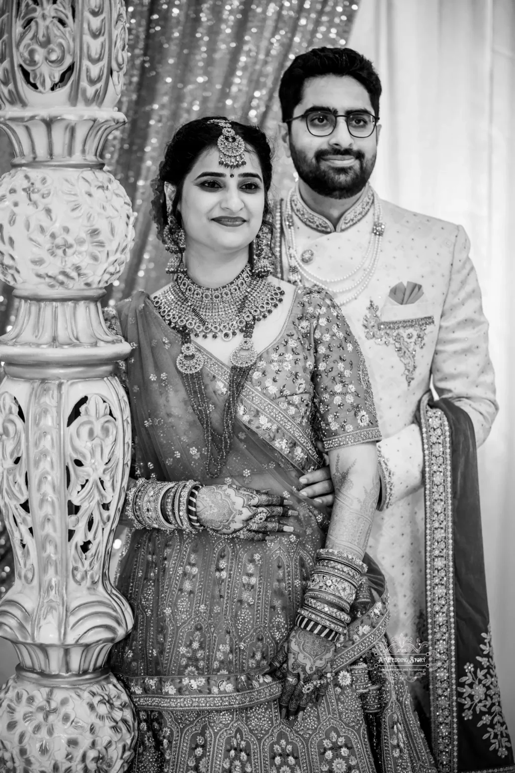 Black and white portrait of the bride and groom in traditional attire, smiling and standing close together.