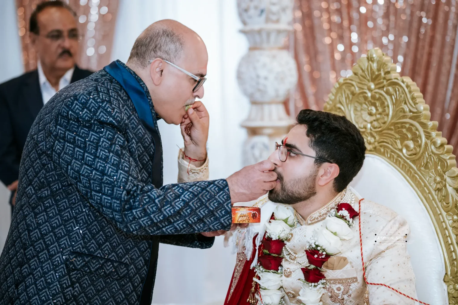 An elder offers a ceremonial sweet to the groom as a blessing during the wedding ceremony.