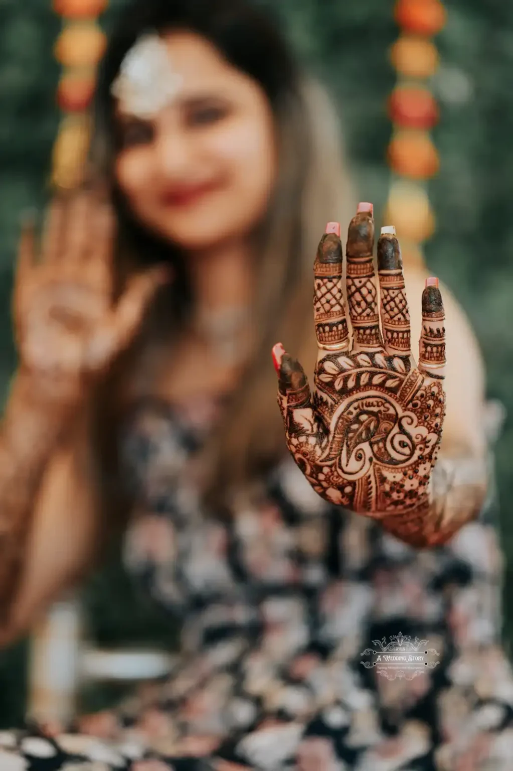 Close-up view of a bride's intricately designed mehndi art on her hand, with the blurred background showcasing her joyful expression and festive decor during a Mehndi ceremony in Wellington