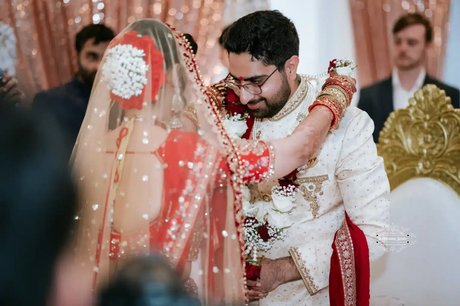 Bride in traditional red attire embraces the groom, sharing a tender moment during the wedding ceremony.