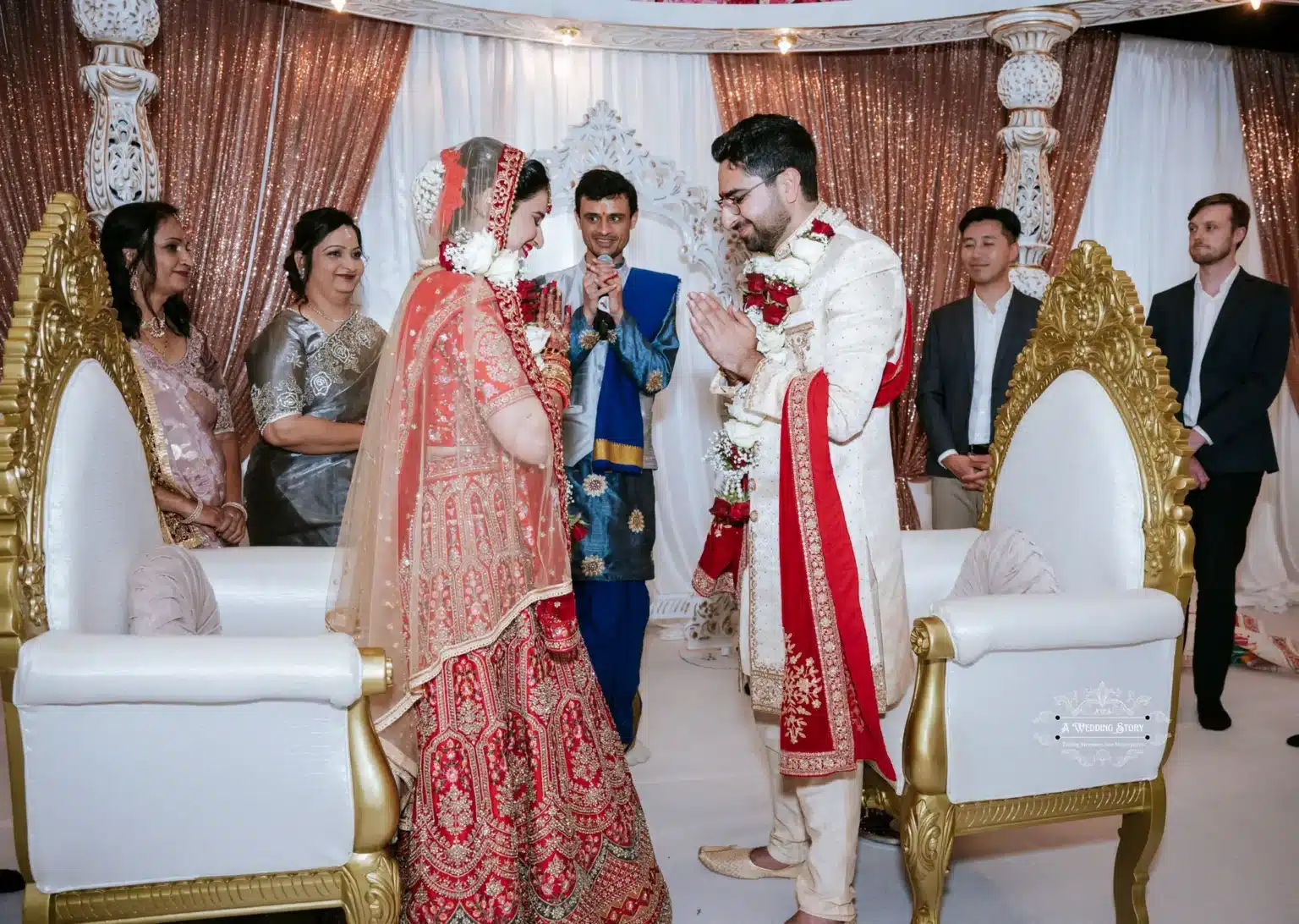 Bride and groom in traditional attire exchange respectful greetings during the wedding ceremony, surrounded by family and friends