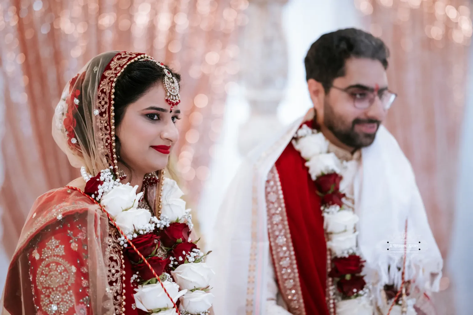 Bride and groom dressed in traditional attire, adorned with floral garlands, standing together during their wedding ceremony.