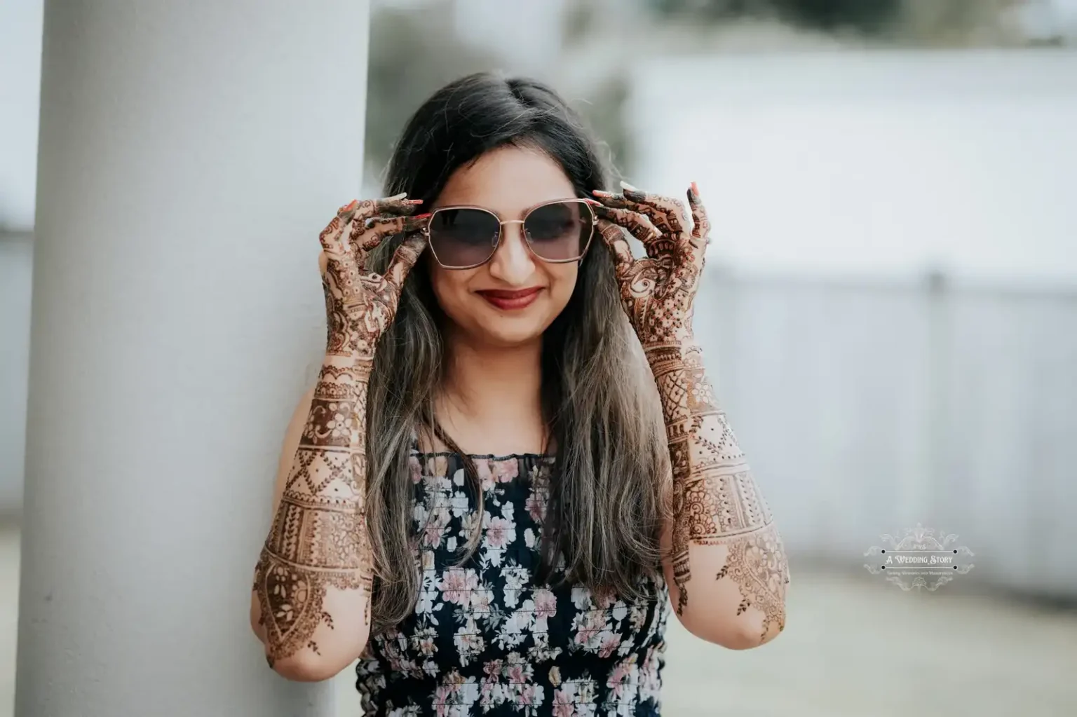 Smiling bride wearing sunglasses and showcasing intricate bridal mehndi designs on her hands, captured during a pre-wedding celebration in Wellington by A Wedding Story