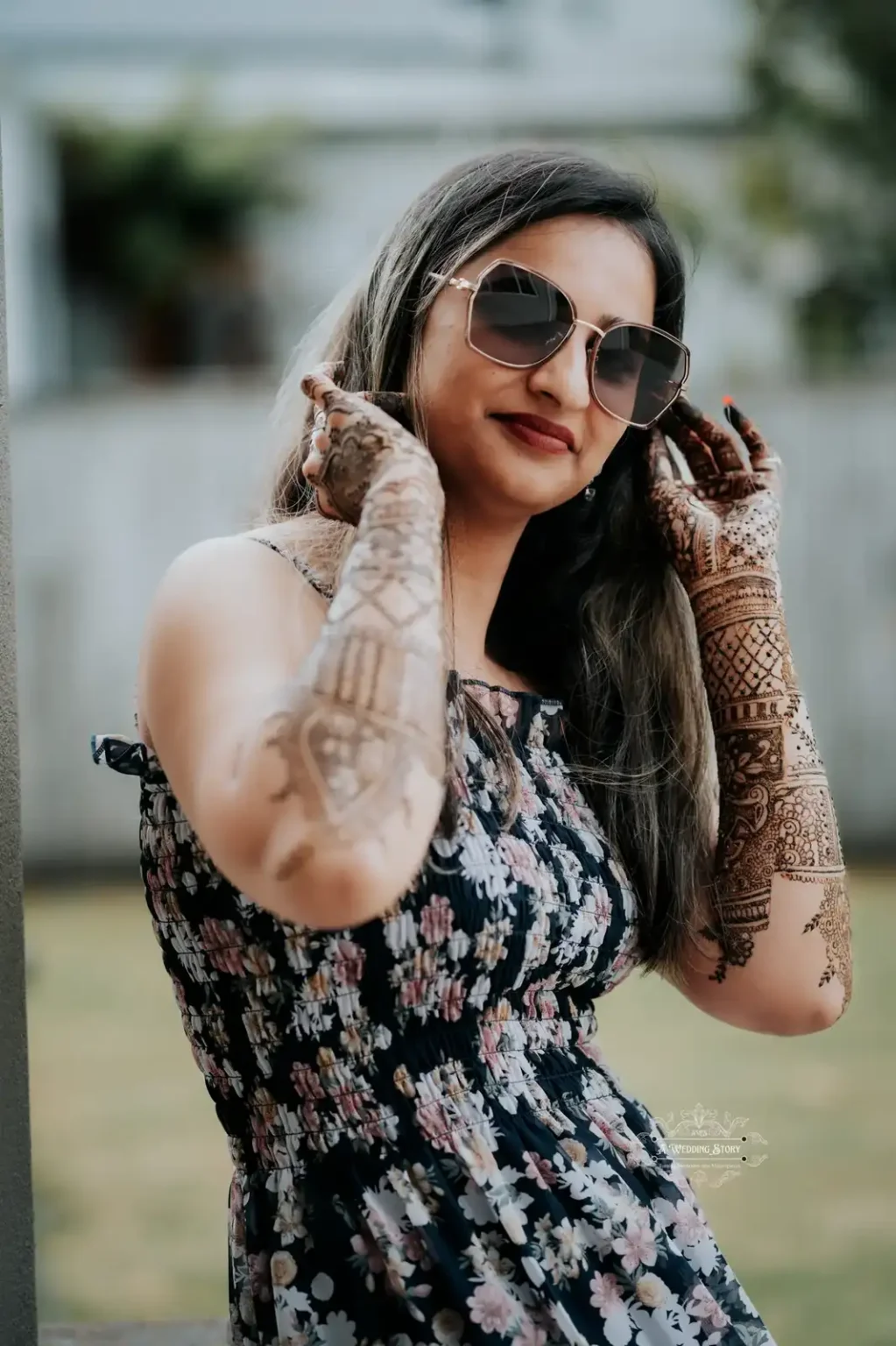 Smiling bride wearing sunglasses and showcasing intricate mehndi designs on her hands, captured during a stylish pre-wedding celebration in Wellington by A Wedding Story