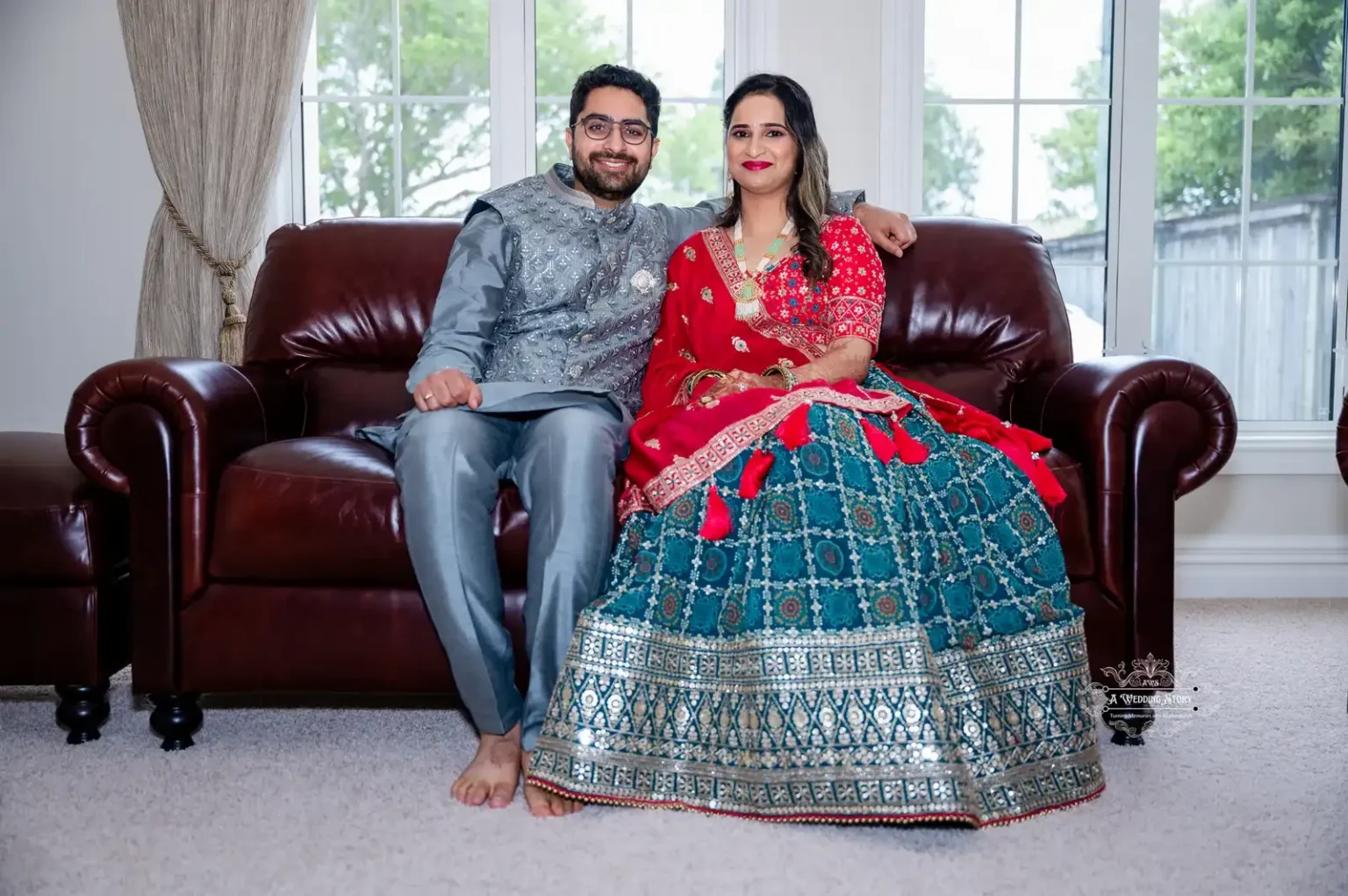 Happy couple in traditional attire sitting on a leather couch, captured by Wedding Photography in Wellington.