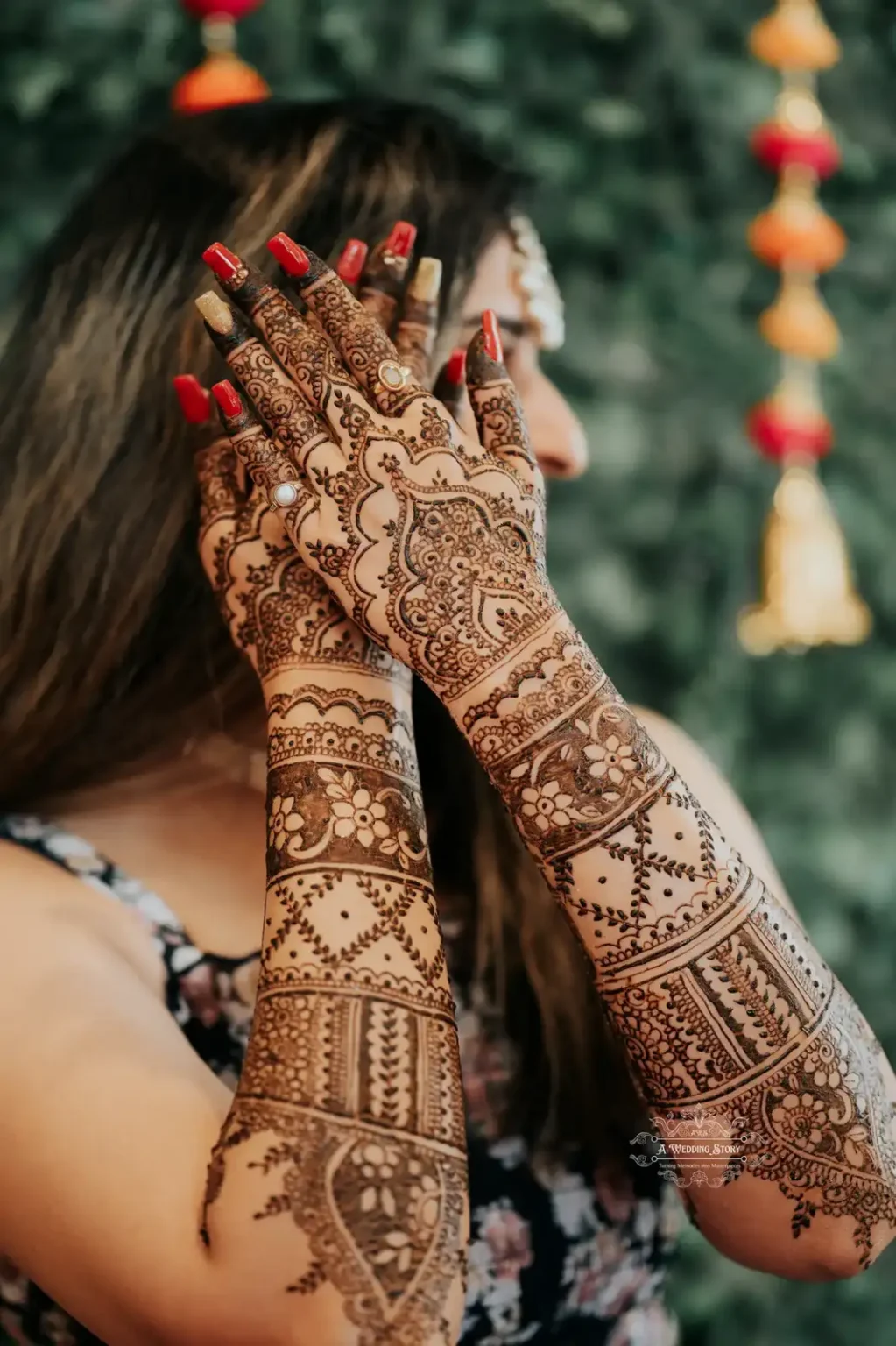 Close-up of the bride's beautifully intricate mehndi art on her hands, elegantly placed near her face, captured with a vibrant green backdrop during a Mehndi ceremony in Wellington