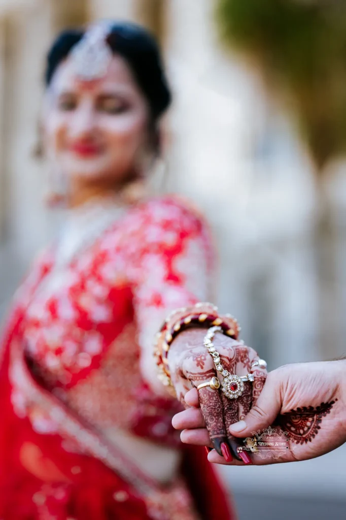 Close-up of bride and groom holding hands with intricate henna and jewelry details during their wedding in Wellington, New Zealand.